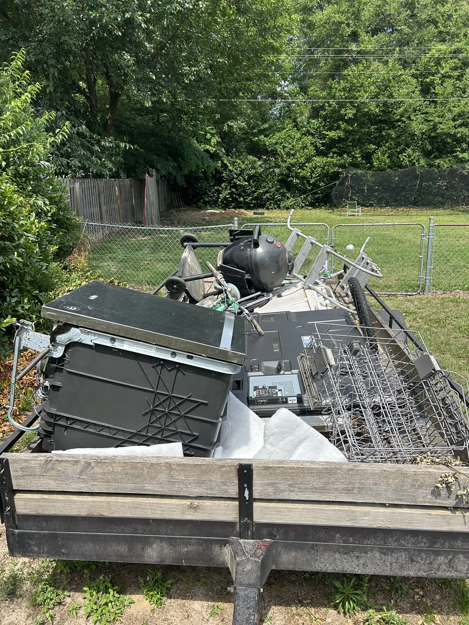 Old appliances and a grill loaded on a flatbed trailer