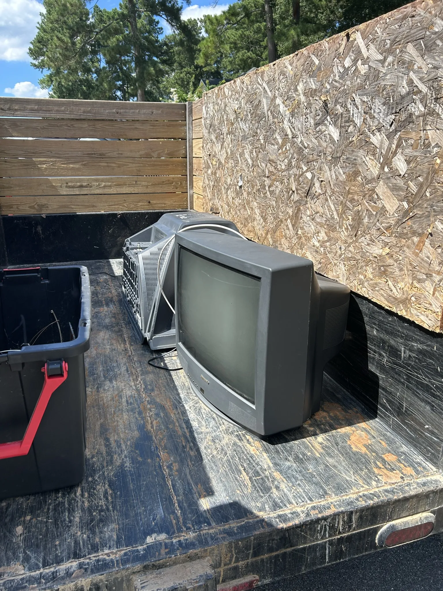 Old tube TVs and a storage bin loaded in the dump trailer