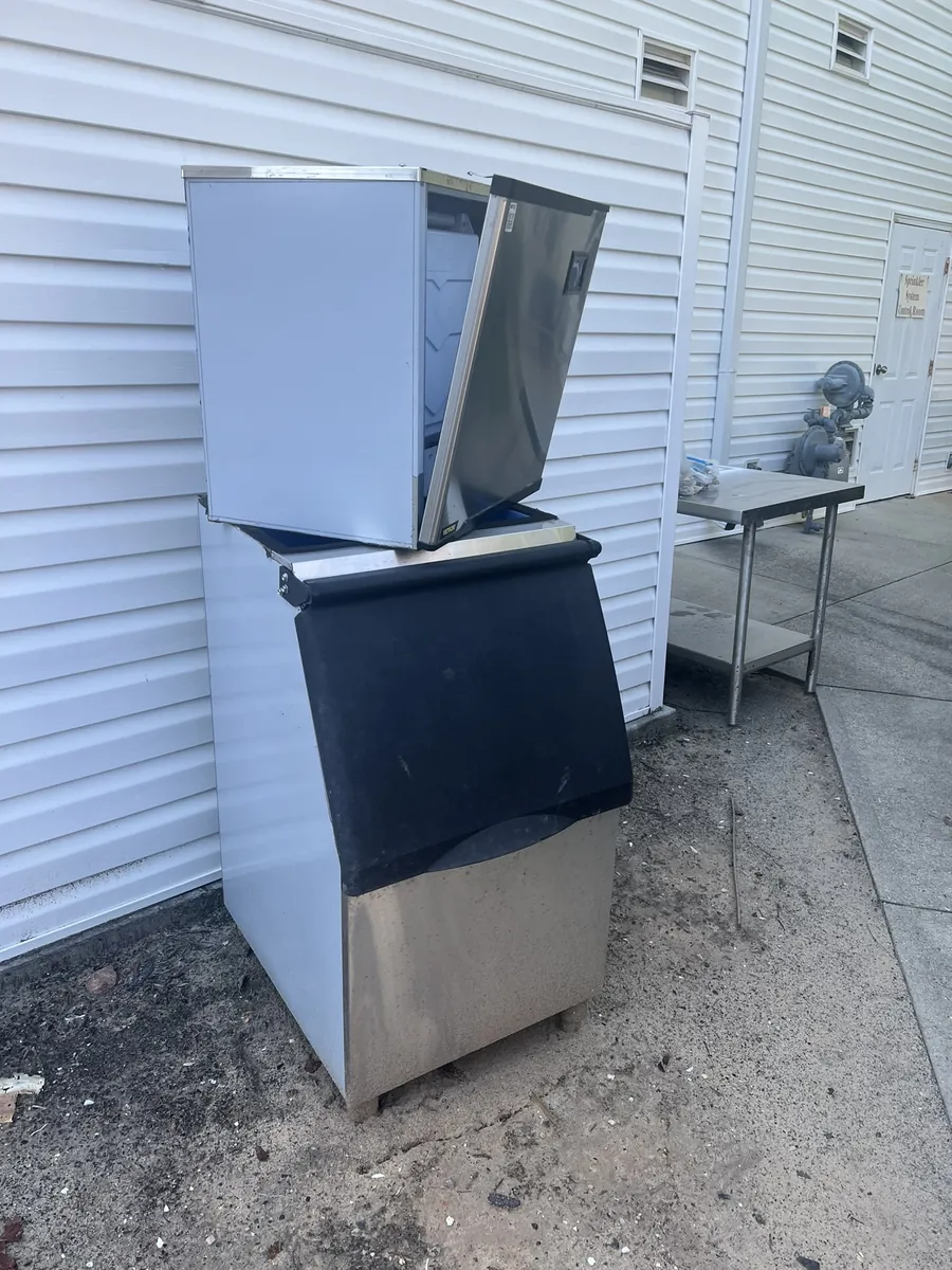 A stainless steel commercial ice machine set out behind a restaurant
