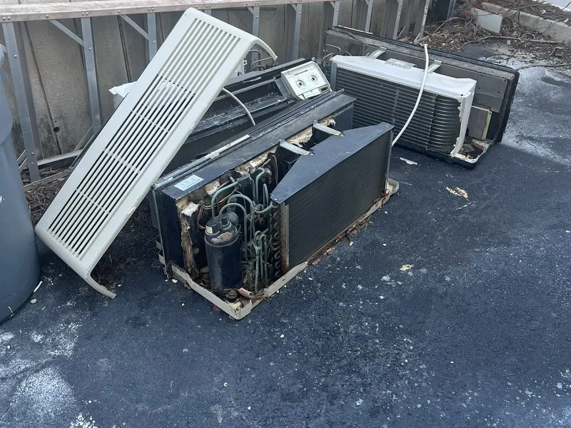 Old wall air conditioning units set out behind a commercial building