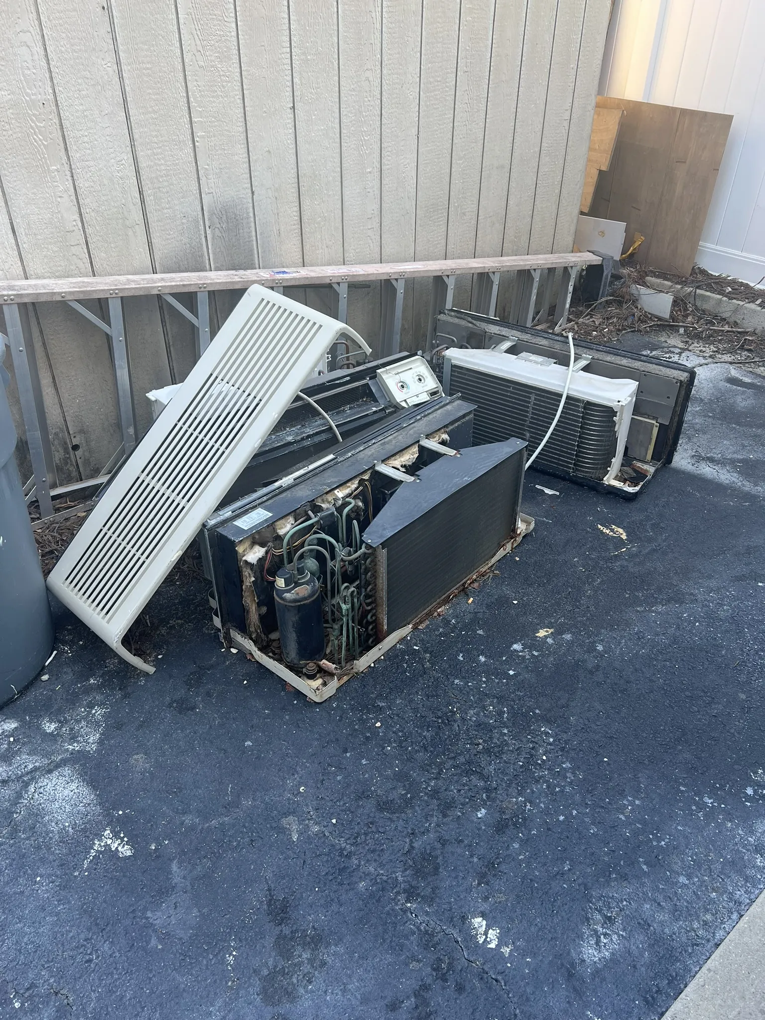 Old wall air conditioning units set out behind a commercial building