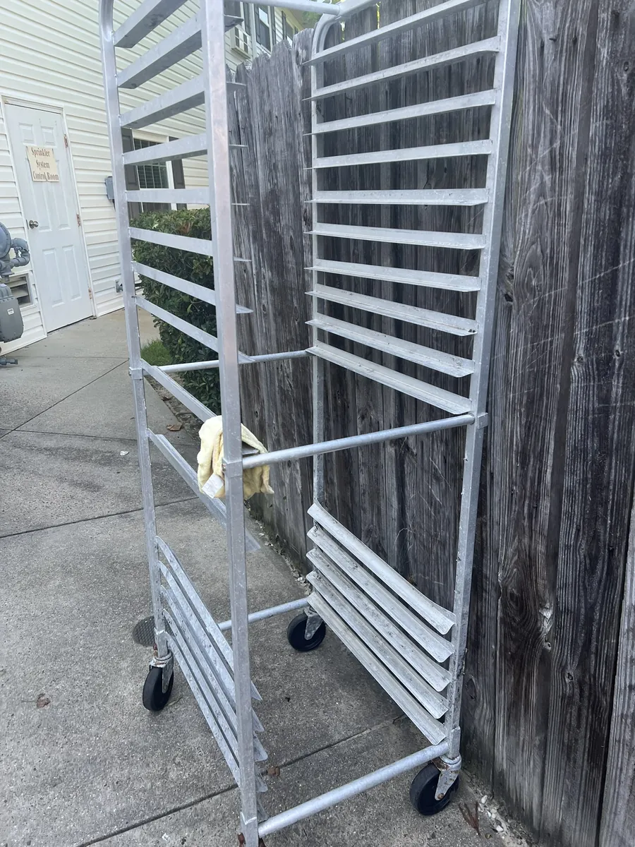 A tall metal sheet pan rack set out behind a commercial kitchen