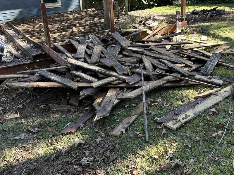 A large pile of old deck boards on the grass beside a house