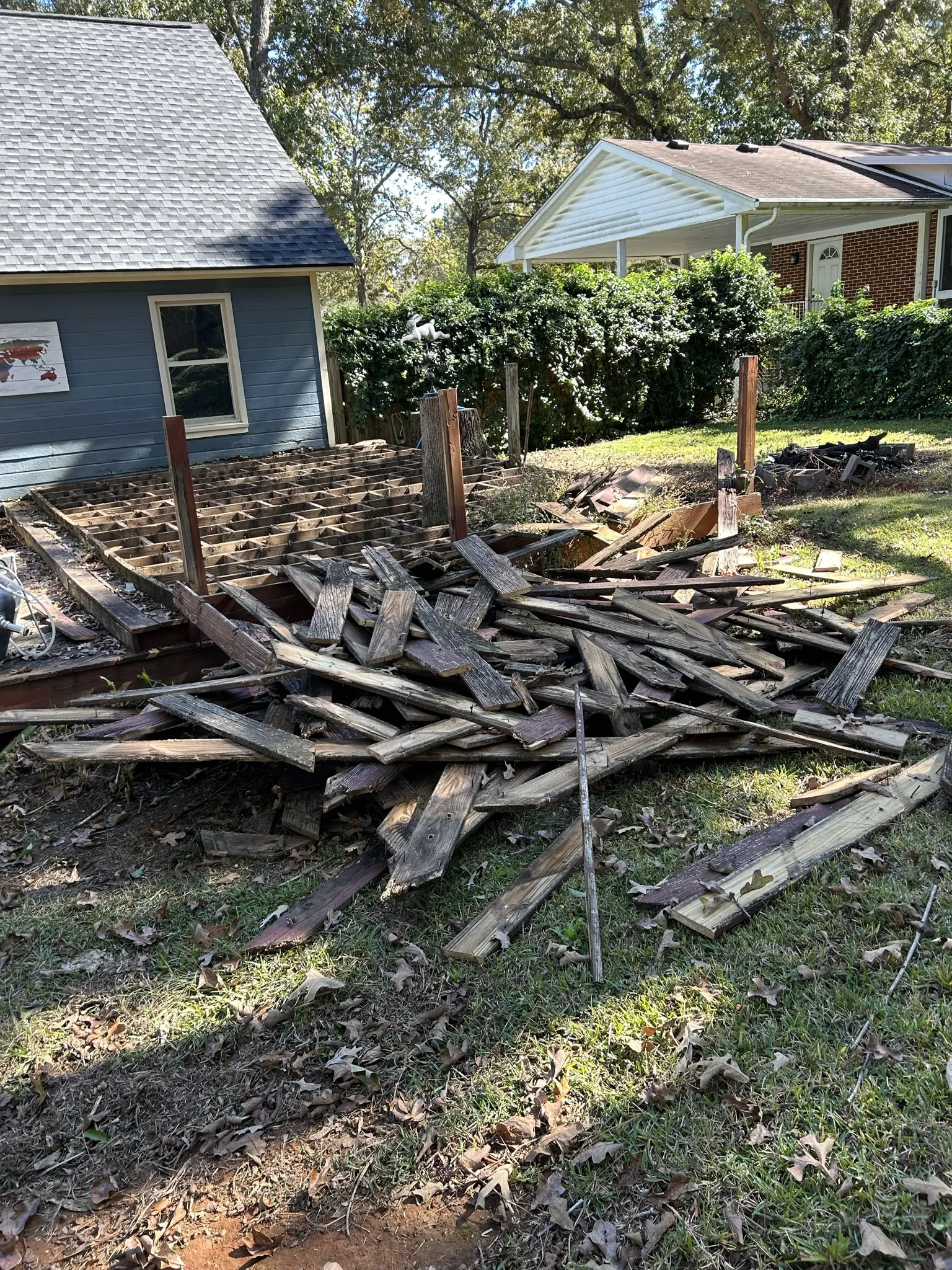 A large pile of old deck boards on the grass beside a house