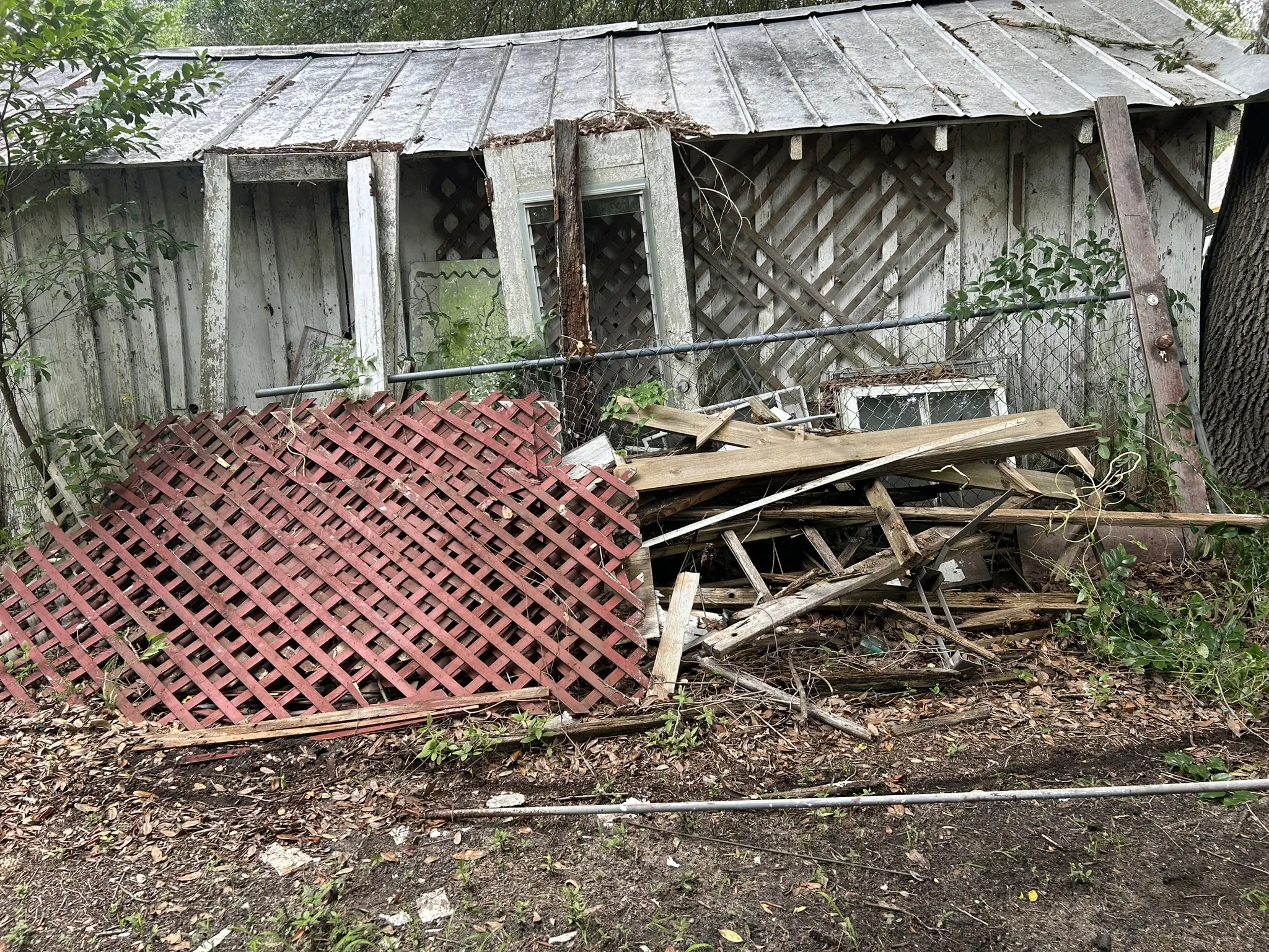 Old red lattice panels and boards piled against a fence