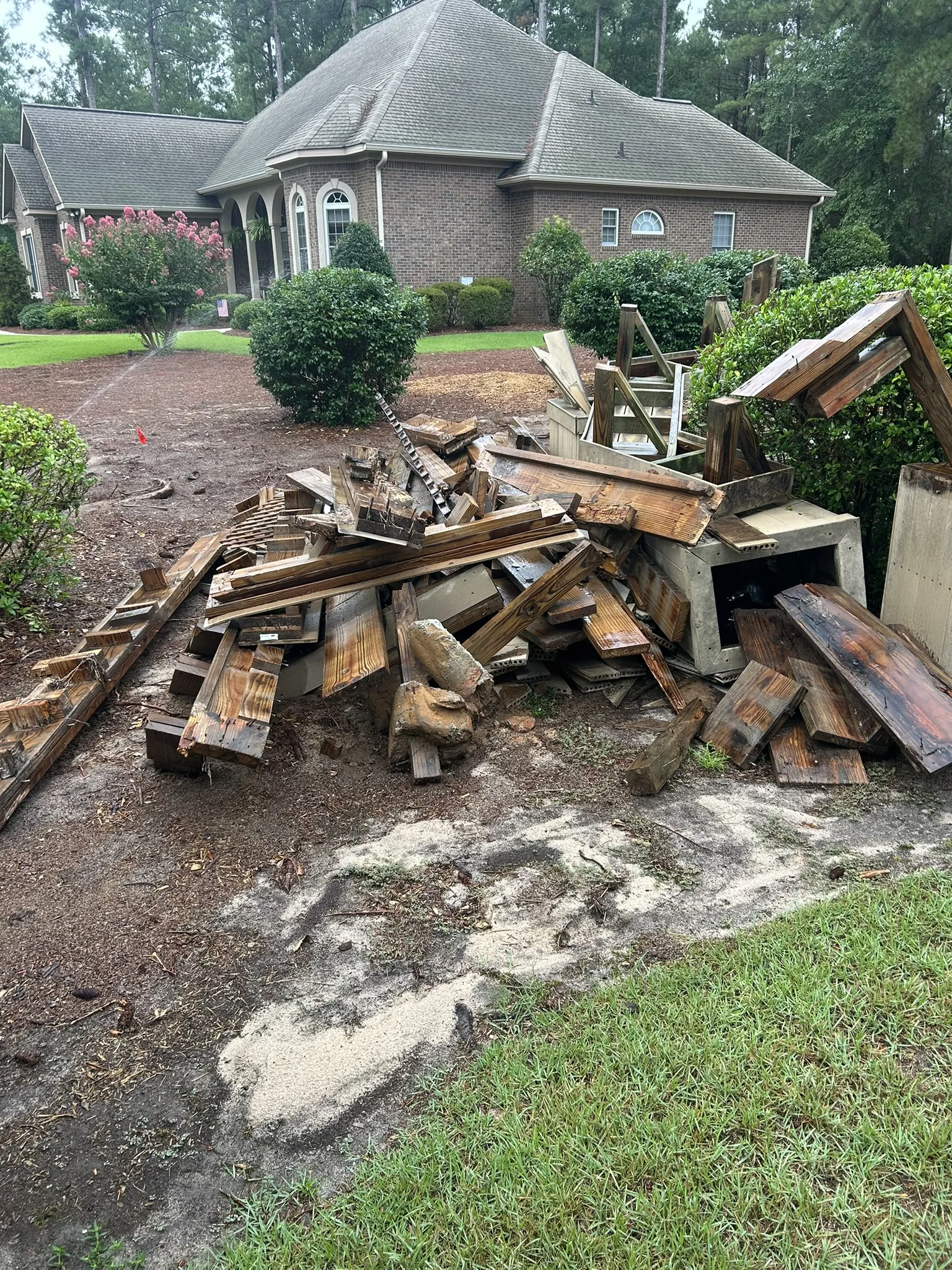 Old landscape timbers and boards piled in front of a brick home