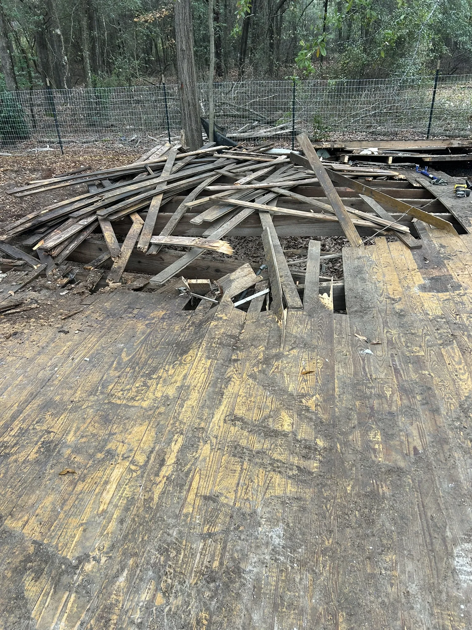 Old deck boards torn out and piled in a fenced yard