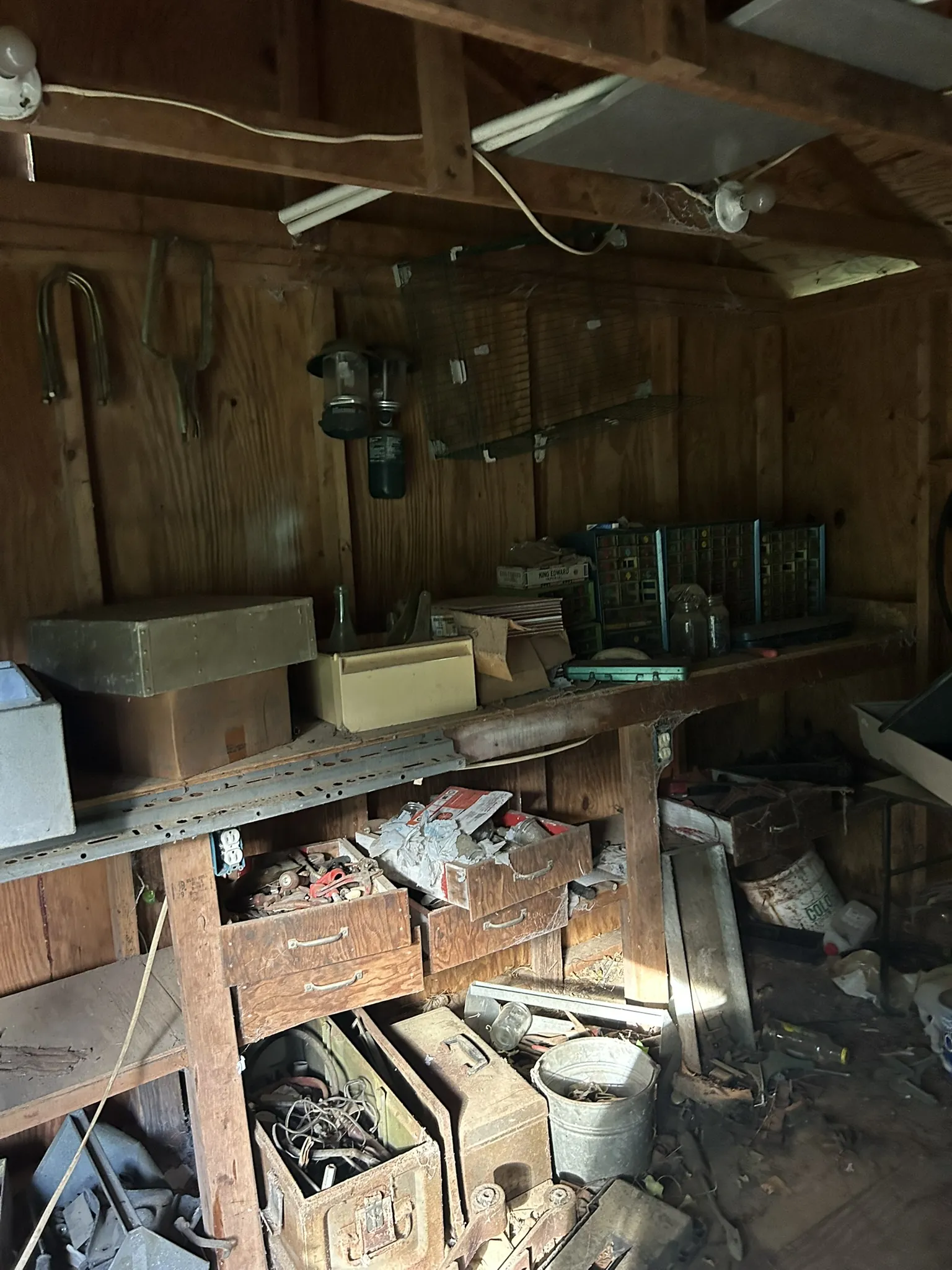 A cluttered workshop with tools, boxes and old belongings on the shelves