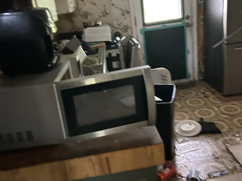 A kitchen crowded with a microwave, appliances and belongings
