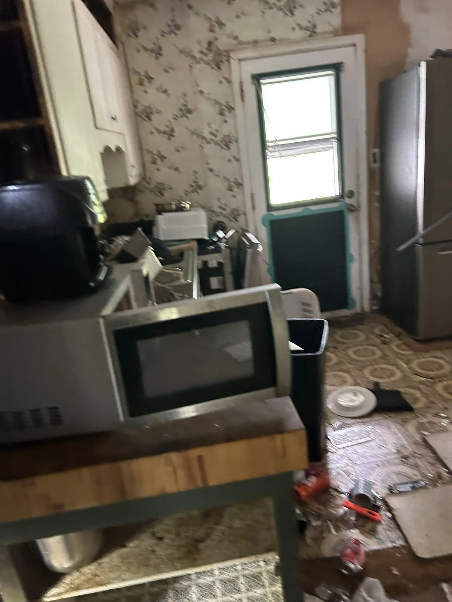A kitchen crowded with a microwave, appliances and belongings