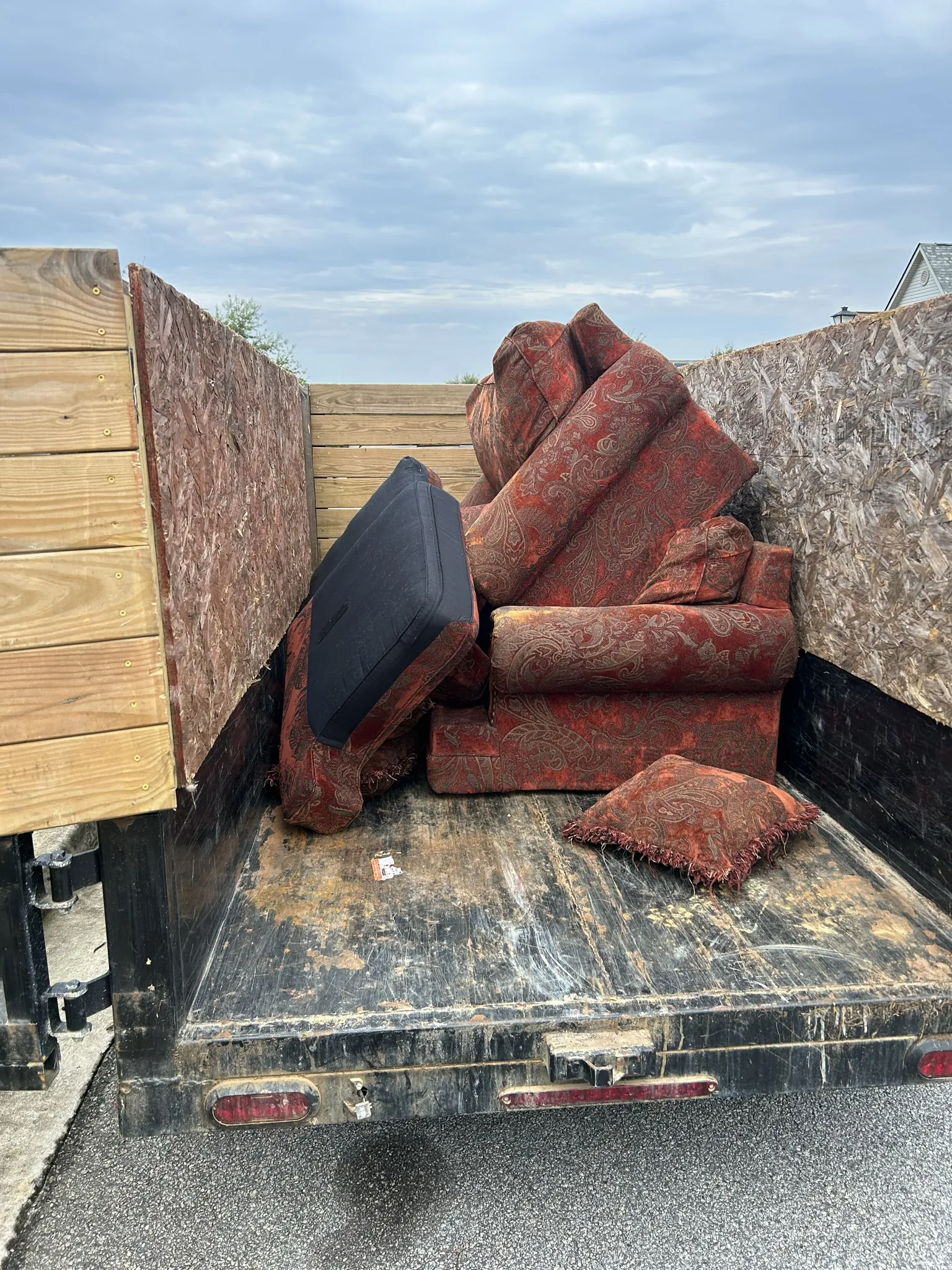 A red patterned couch and chair loaded in the dump trailer