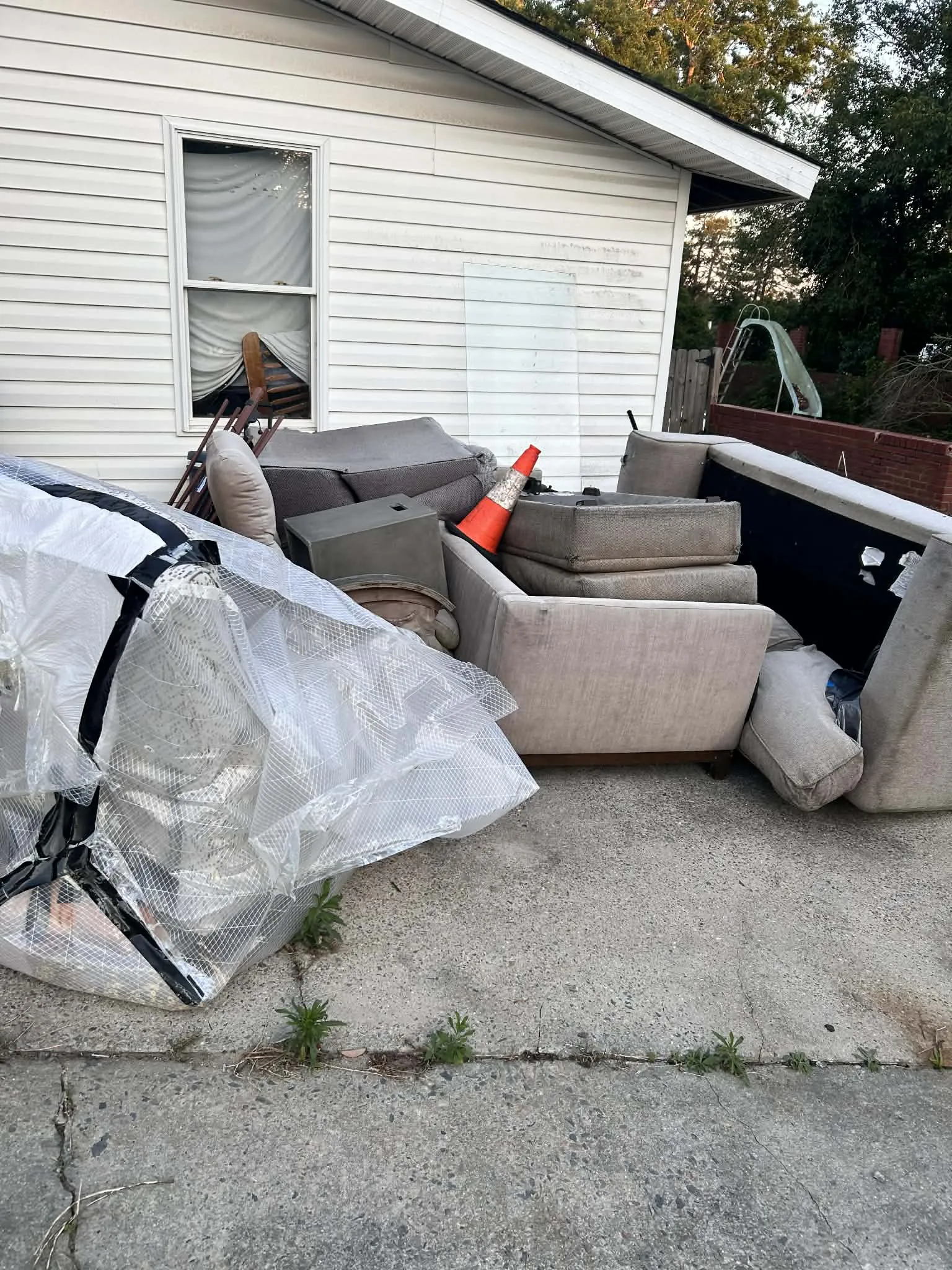 An old sofa, cushions and furniture set out beside a house