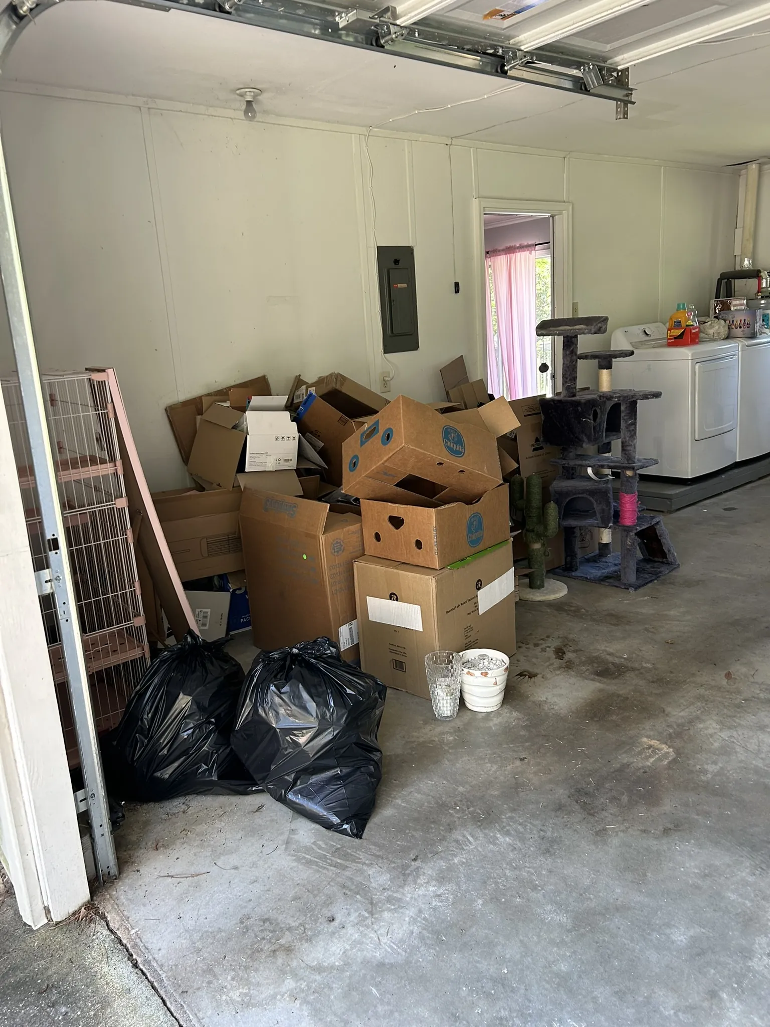 Boxes and trash bags stacked in a garage