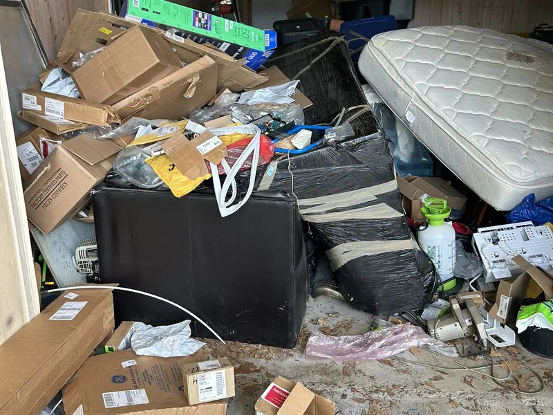 A garage full of boxes with a mattress leaning against the pile