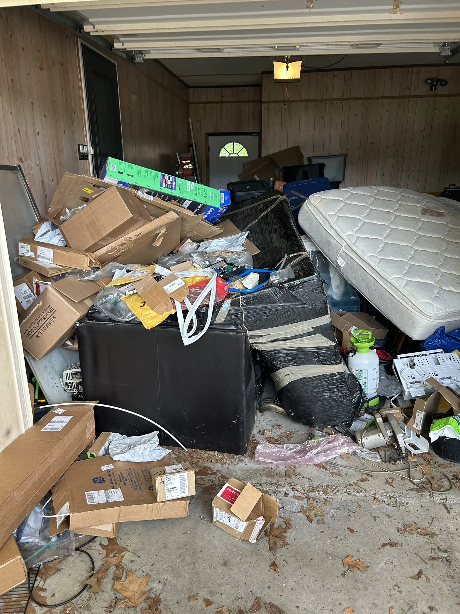 A garage full of boxes with a mattress leaning against the pile