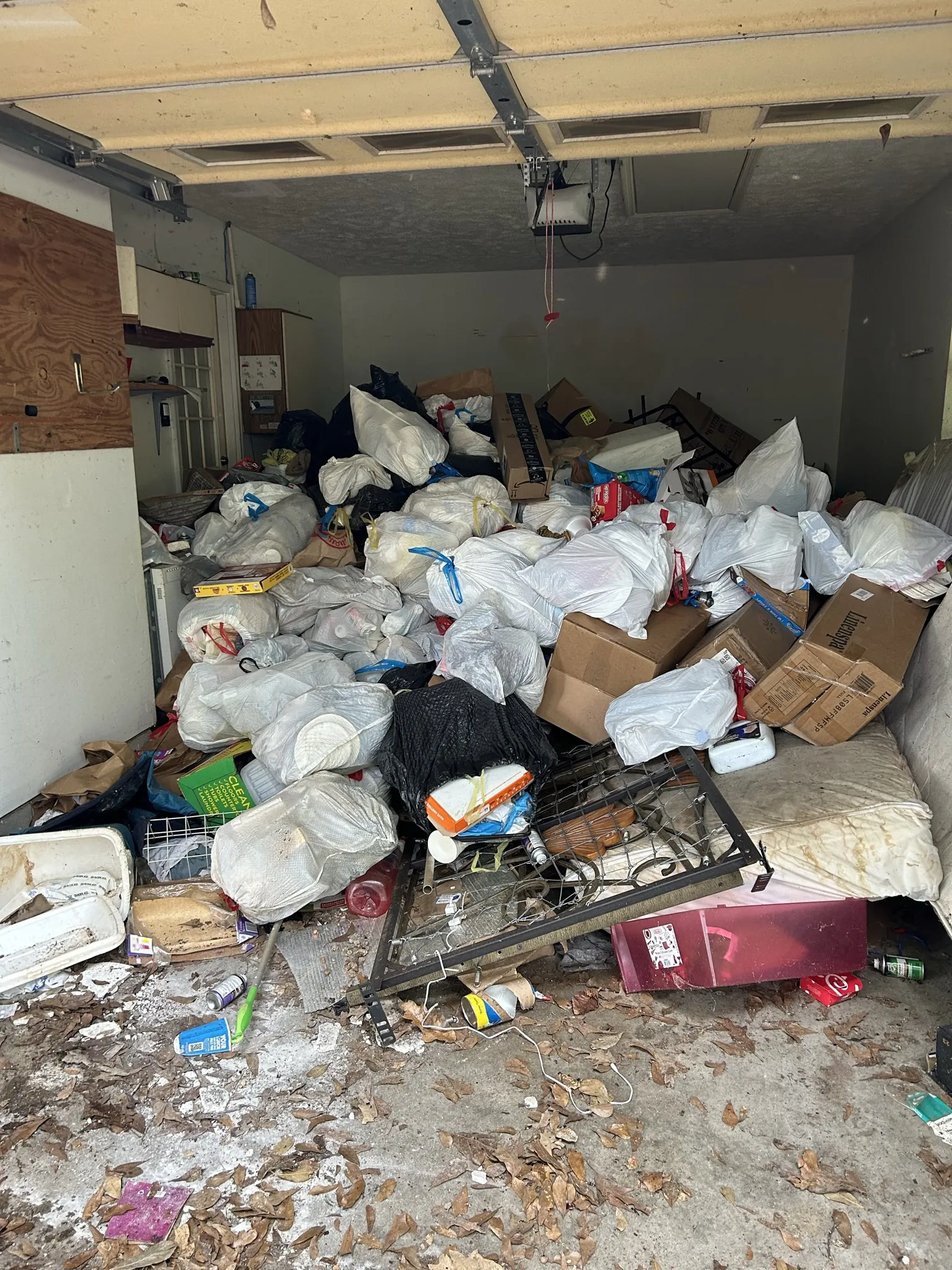 A two-car garage packed with bags, boxes and a bed frame