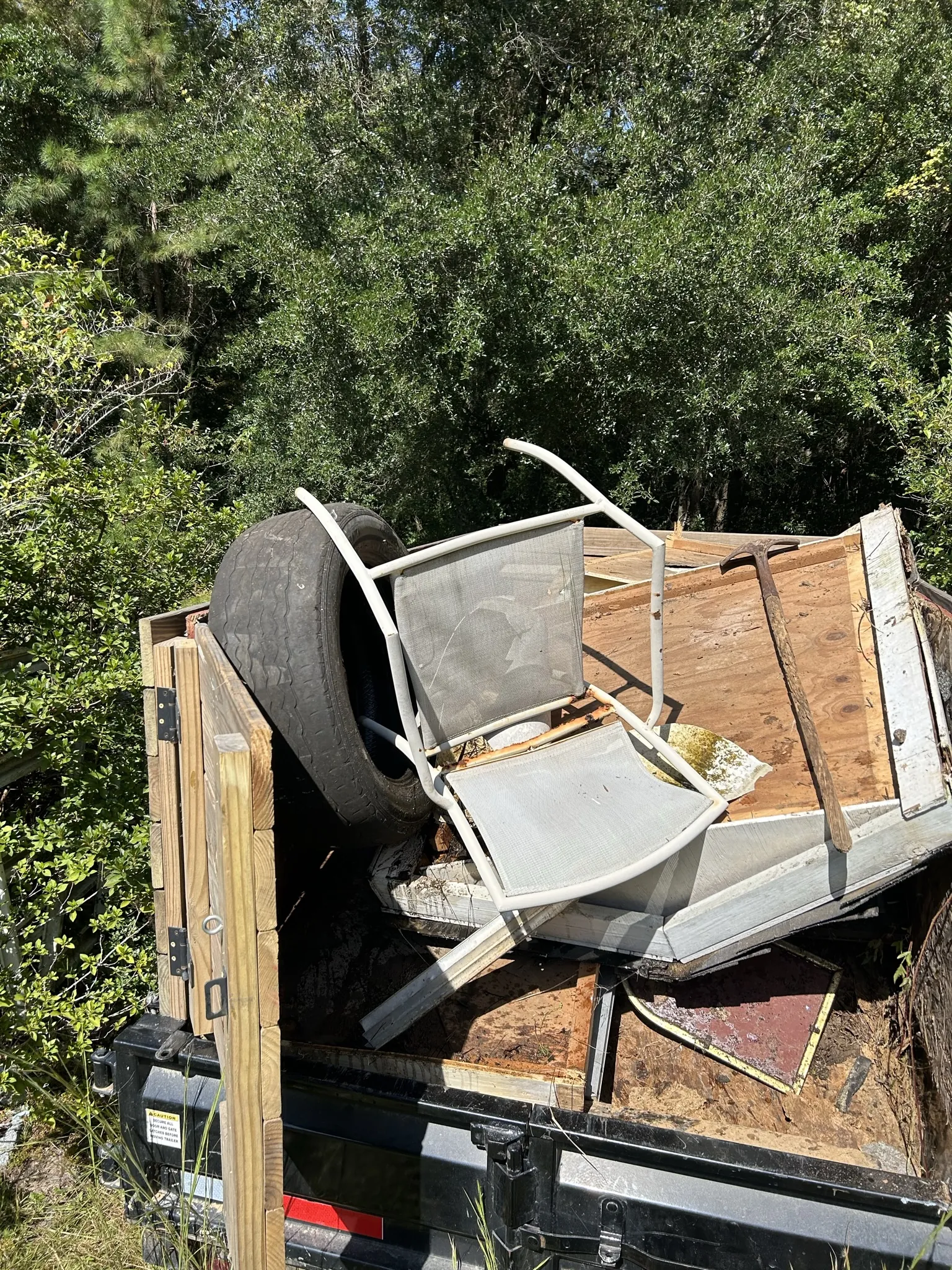 An old patio chair, a tire and boards loaded in the dump trailer