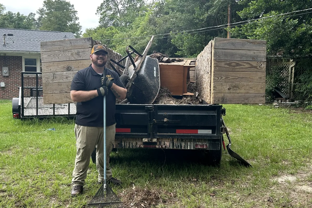 Pat Boatwright holding a rake in front of his loaded dump trailer