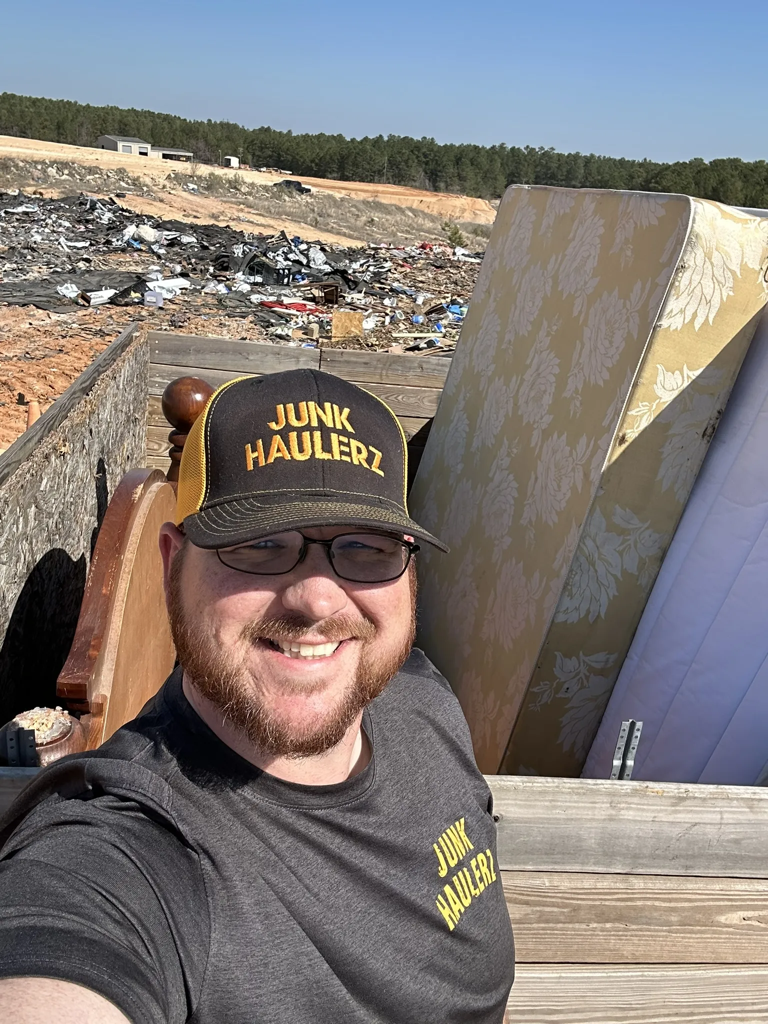 Pat Boatwright taking a selfie beside a mattress in the trailer at the landfill