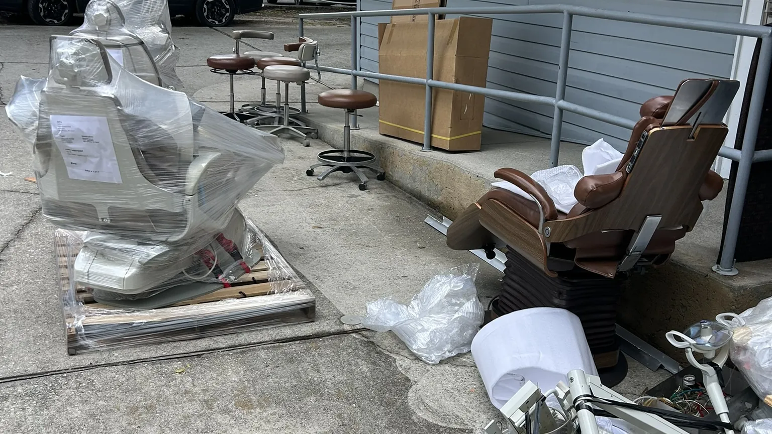 Dental chairs, stools and equipment set out on pallets beside an office