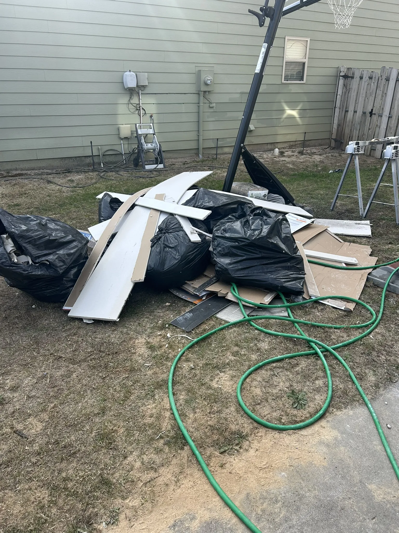 Trash bags and old panels piled beside a house