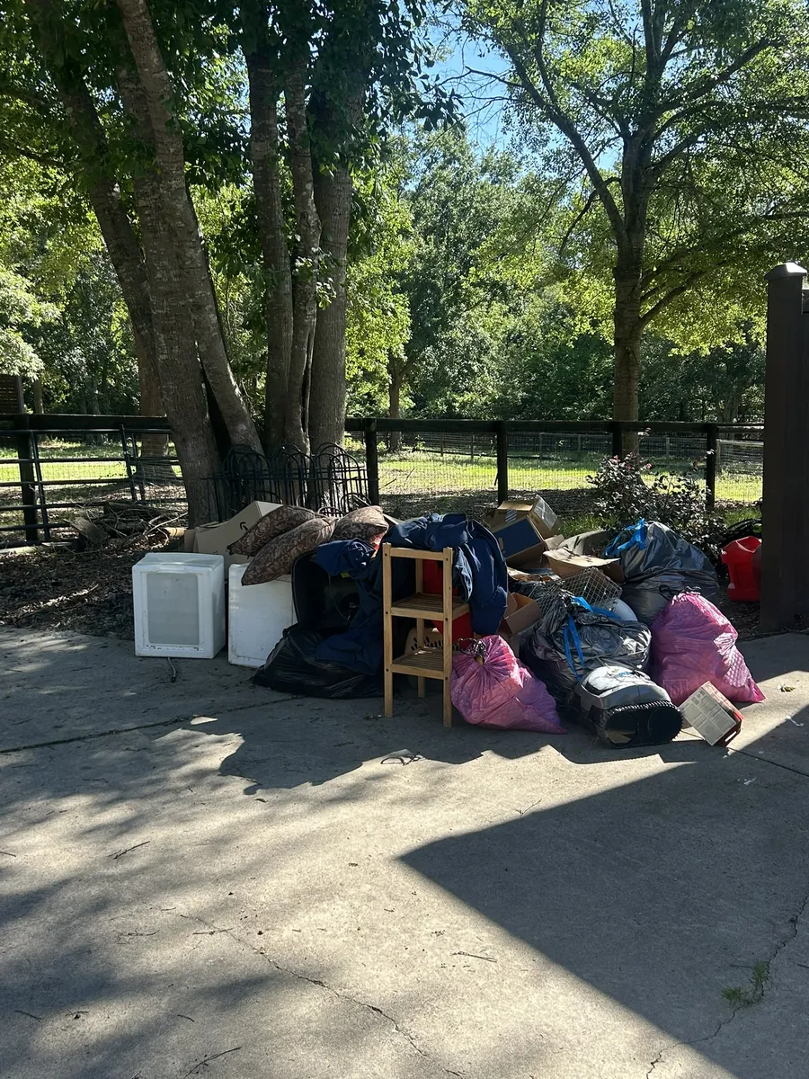 Bags, small furniture and appliances piled at the end of a driveway