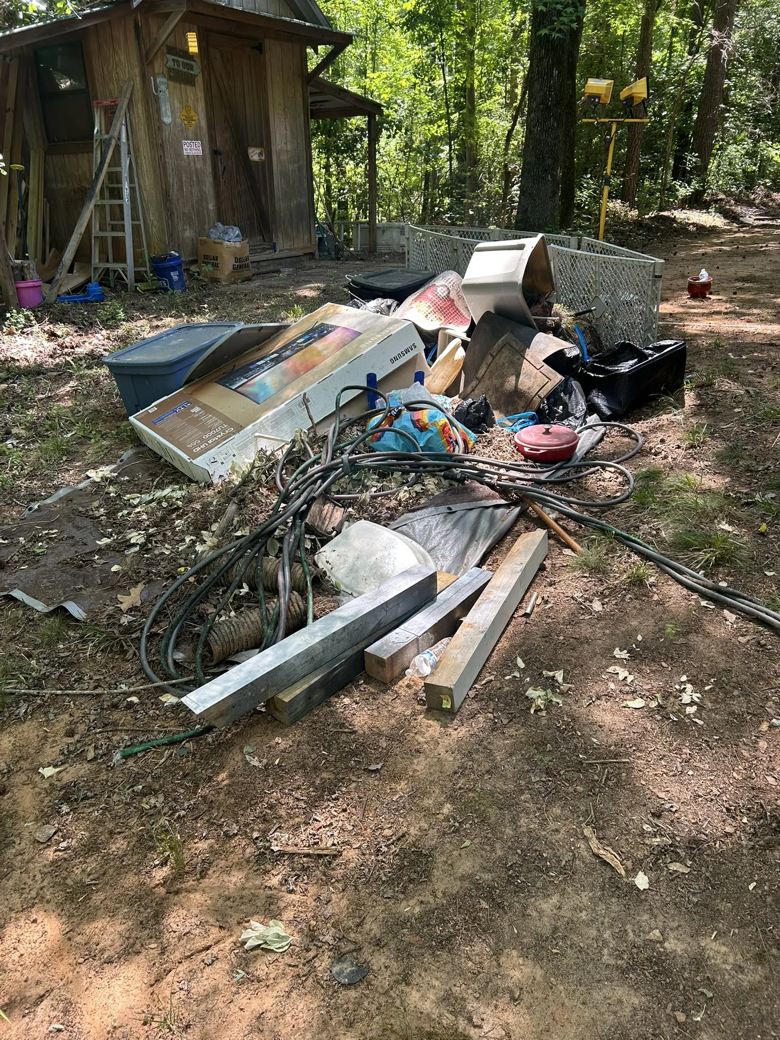 Old panels, wire and household items scattered in a wooded yard