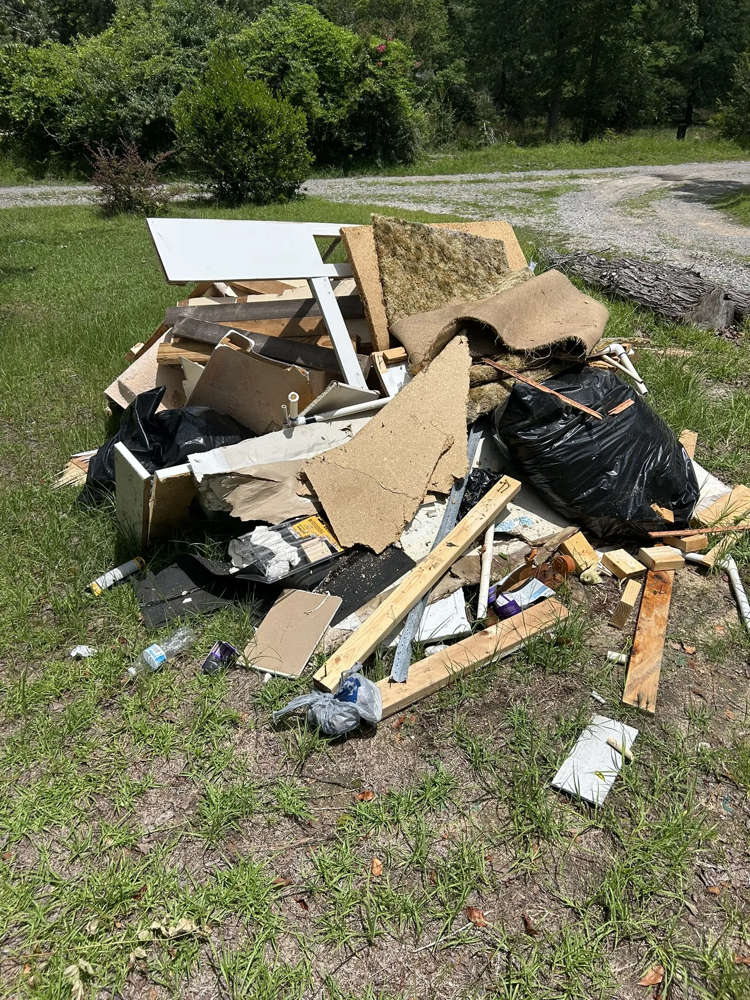 A pile of cardboard, trash bags and boards in a yard
